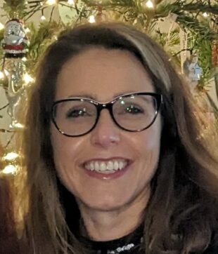 Portrait image of Donna Medd. Brown hair, black glass, big smile.