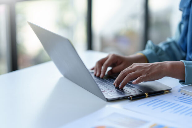 Close up of a woman typing on a laptop computer on a desk